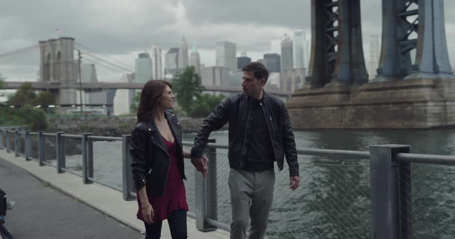 Couple meets and kiss under a bridge near a city