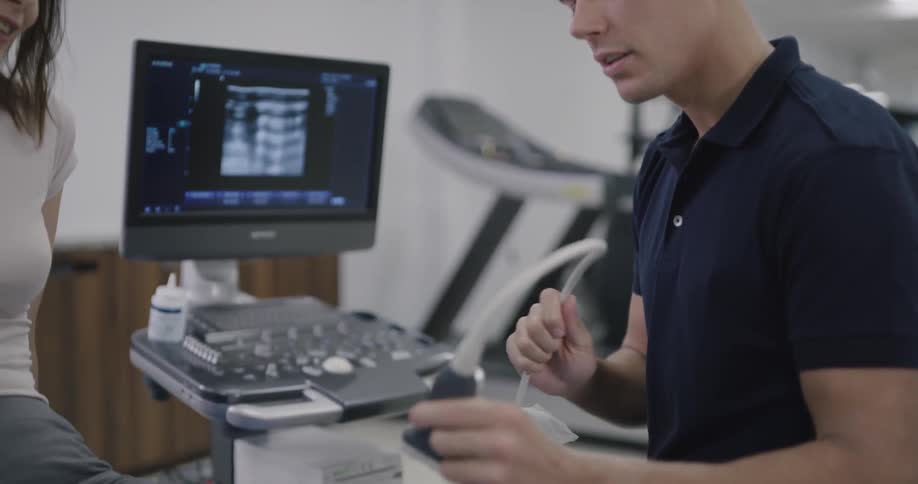A man is using a sonogram on a womans knee