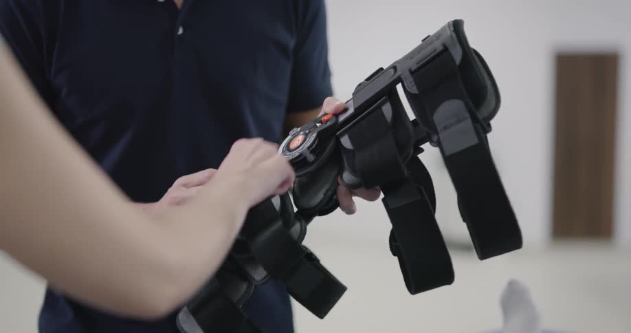 A man is holding a knee brace and adjusting it