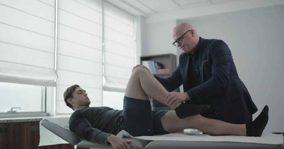 Man inspects another mans knee and bends it