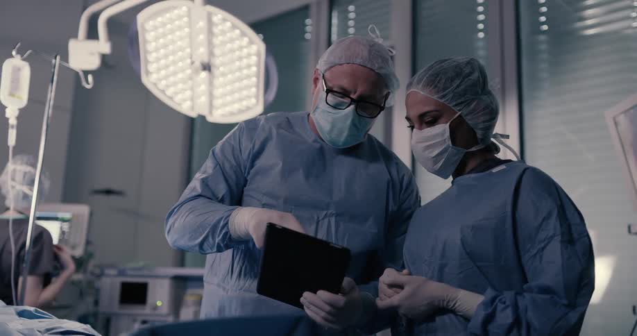 A nurse and doctor using a tablet in an operating room