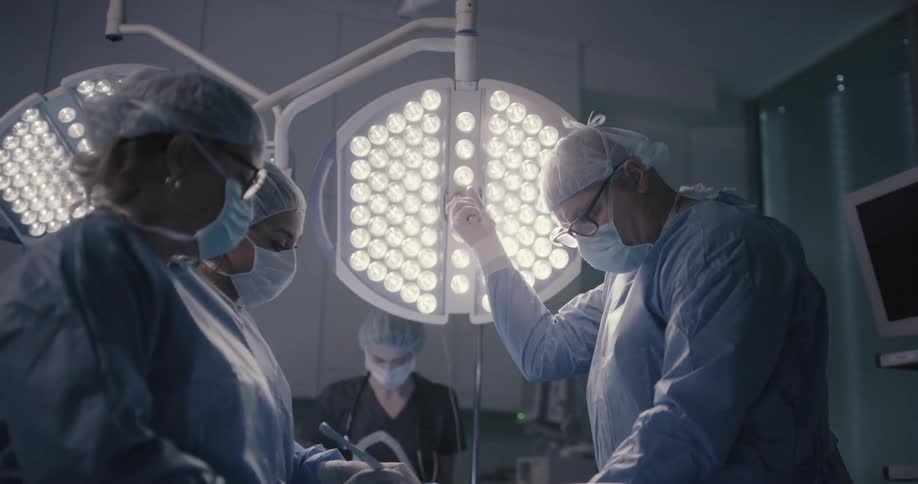 A surgeon and nurses work on a patient in a surgical room
