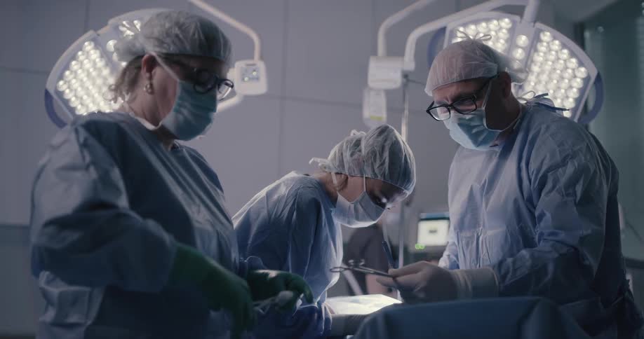 Nurses and surgeons pass instruments back and forth during a surgery