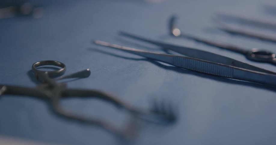 A surgical instrument is picked up and set down by a gloved hand