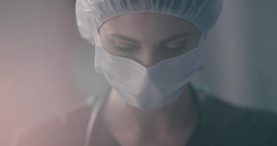 A medical professional wears a mask and cap