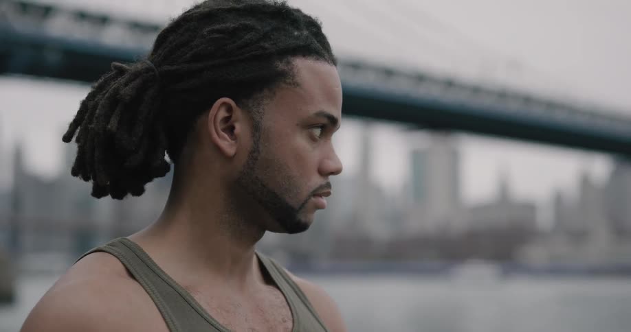 Black man looking at the river under brooklyn bridge