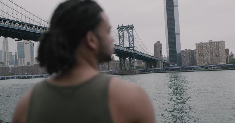 A man is standing outdoors looking at the ocean