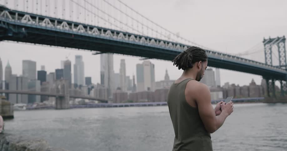 Buffed man play with his phone on the river bank
