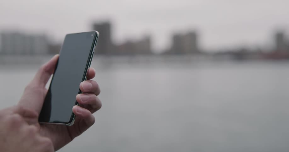 Man uses smart phone on a cloudy day