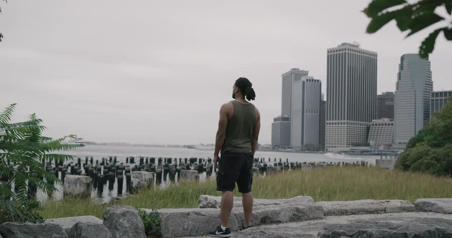 A man jogs over to the water by the city