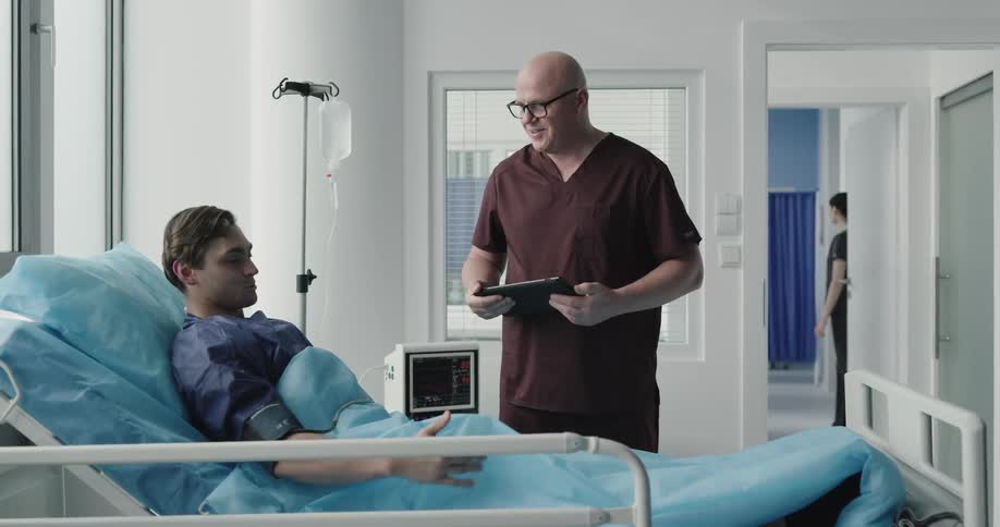 Male doctor showing something to the patient at the hospital room