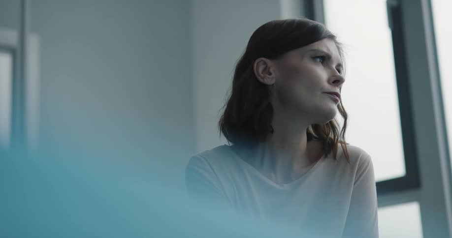 A woman sits down and looks out a window