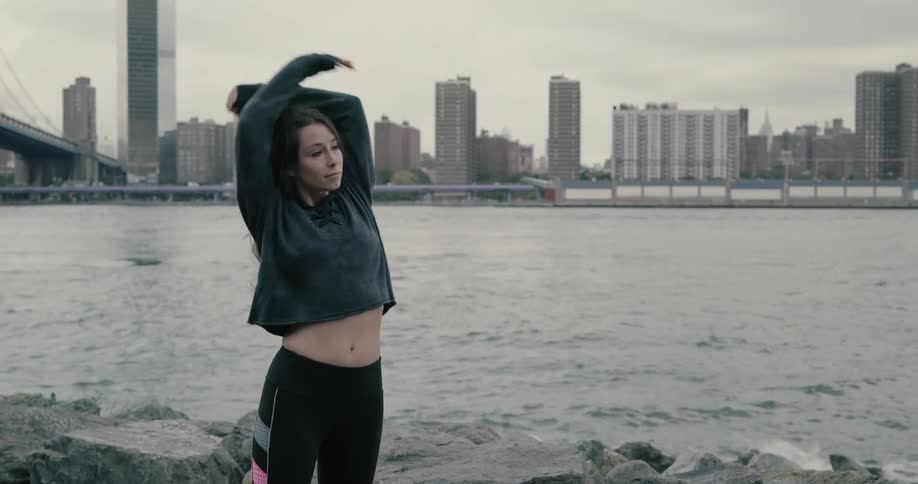 Young woman exercising near the riverbank on the cloudy days