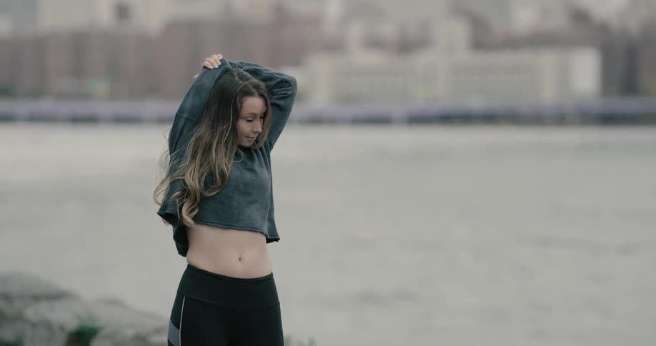 Woman on sportswear stretching at city riverbank