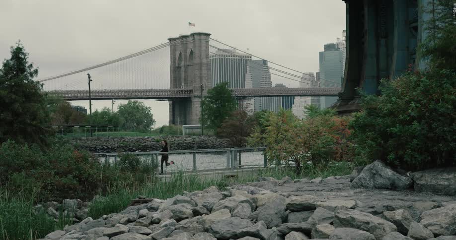 A woman running along a path in a park near a stream