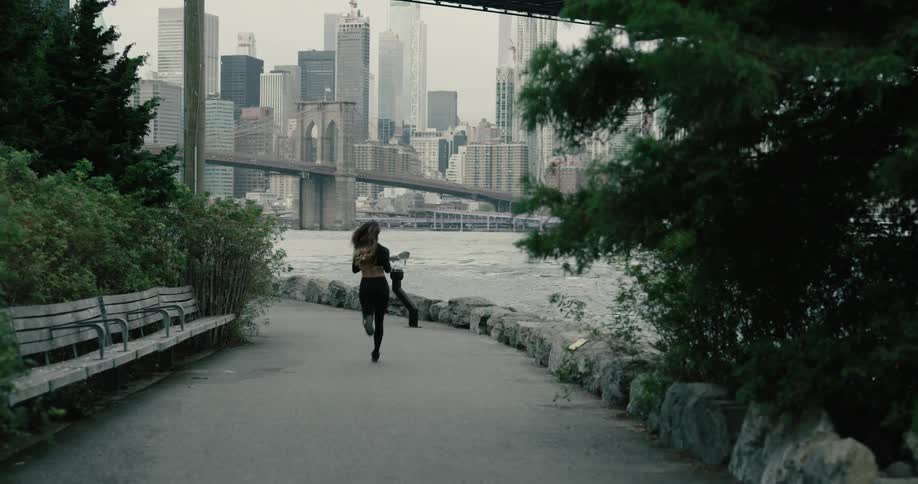 A woman jogs down a trail along the water near downtown