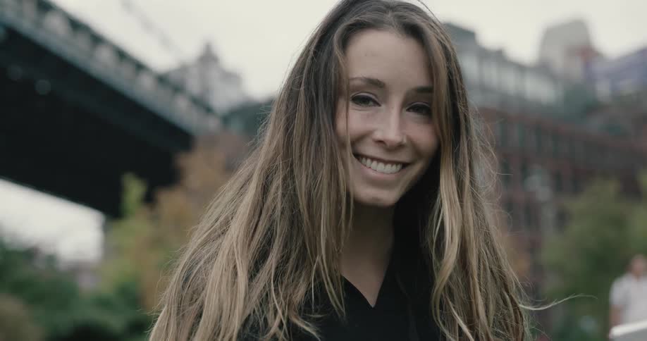 A woman standing outdoors in a city smiling into the camera