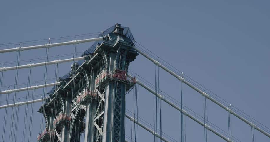 The main cables and suspension cables on a bridge tower against a blue sky