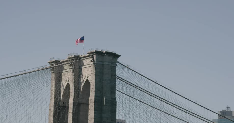 A flag blows in the wind on the top of a bridge