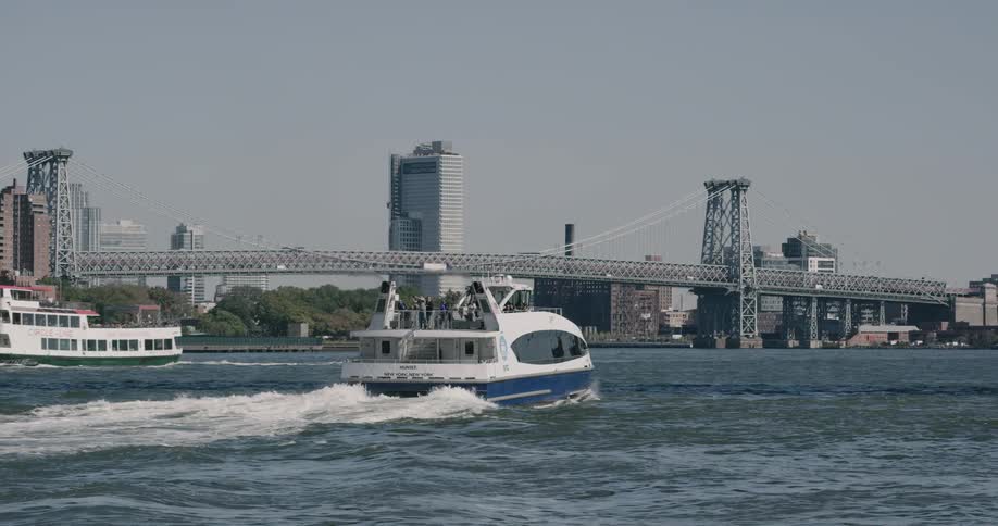 Boats cruise through ocean near bridge and city