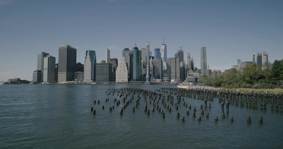 Posts stick out of ocean water with city scape on horizon