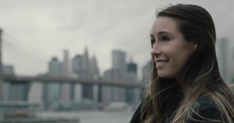 A woman smiles as she stares across the water to new york city