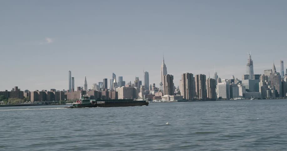A towering metropolitan area of a city that is filled with towering skyscrapers is seen from across a large body of water