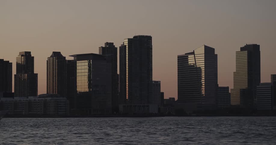 A large boat sails through the water in front of a city skyline