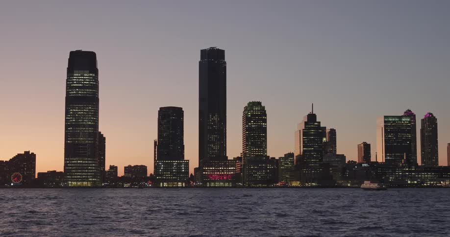 A city skyline on the ocean at sunset