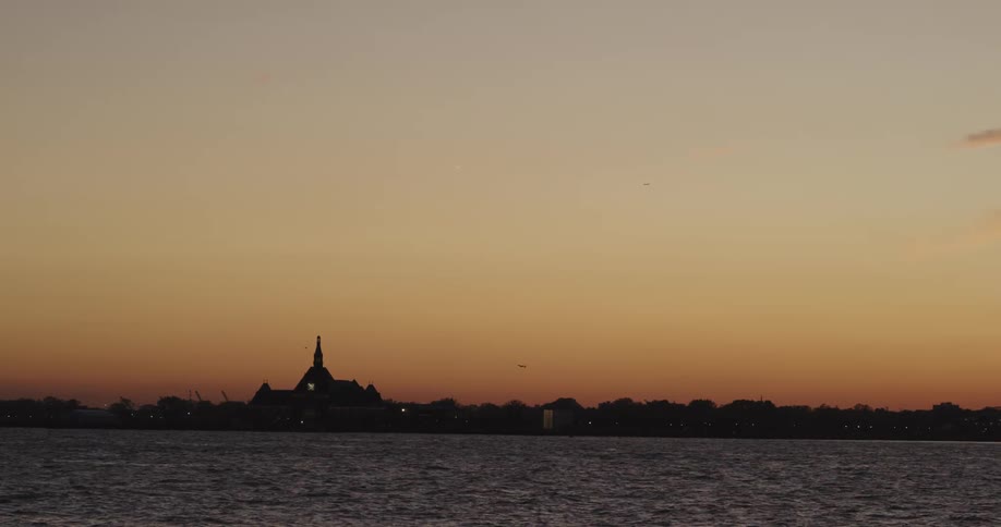 A lake flows in front of a silhouetted horizon at dusk