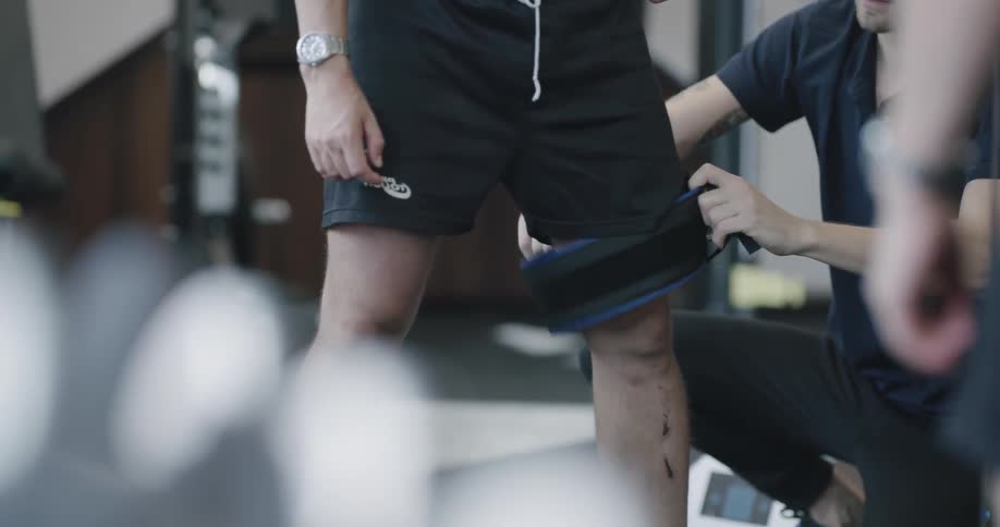 A trainer straps something until a mans thigh