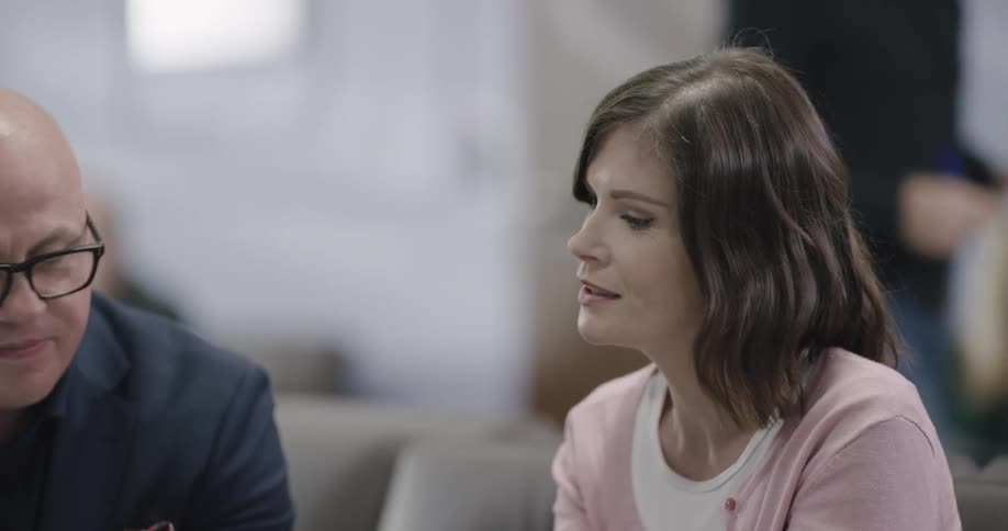 A man shows a tablet screen to a woman