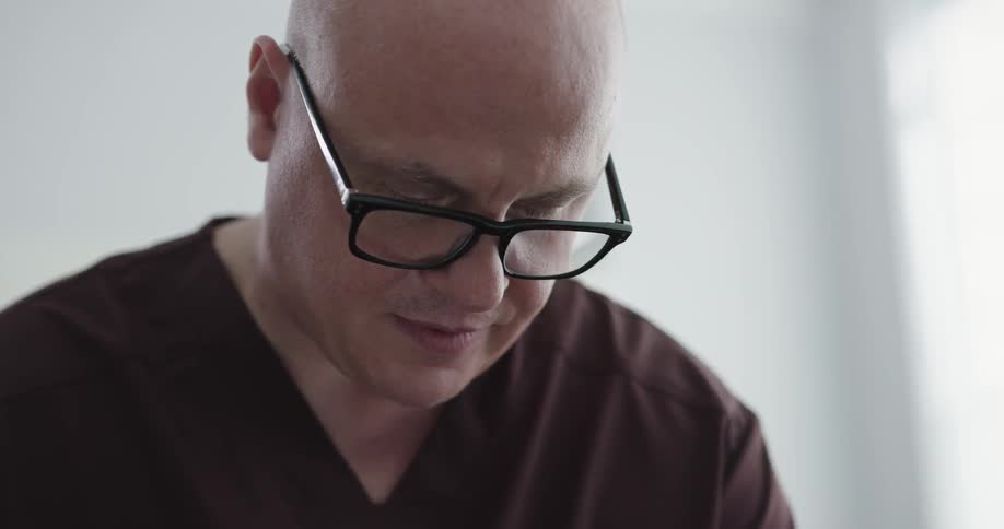 Bald man with glasses talking to someone
