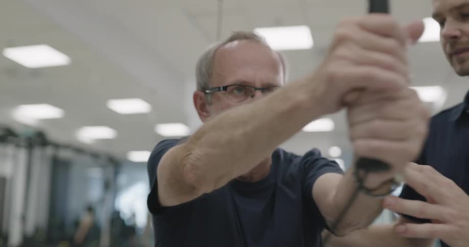 A young man helps an elderly man exercise