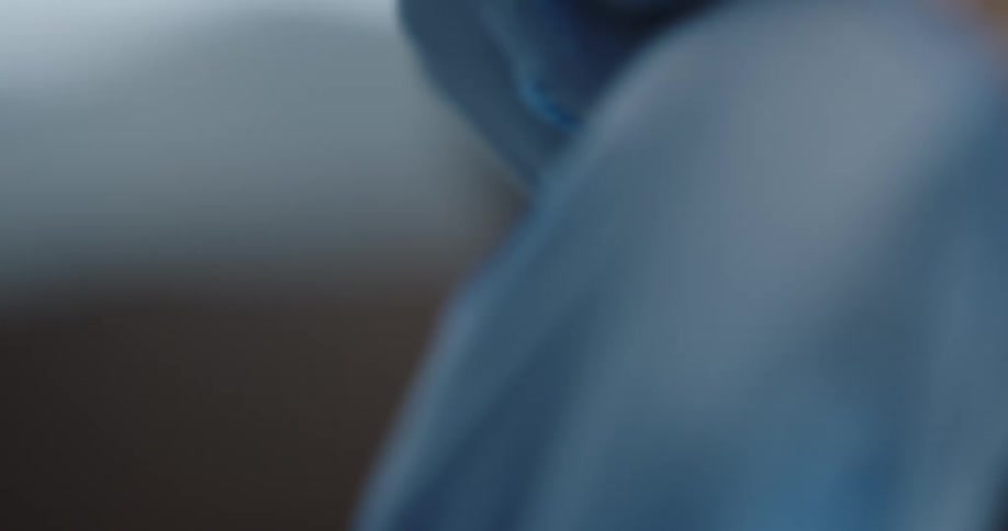 A woman puts a blue glove on her left hand