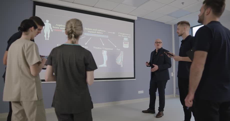 A man doing a presentation with a screen to a group of people and nurses