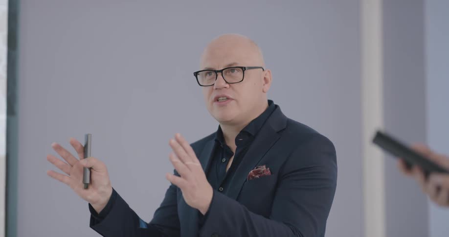 A man stands in front of others and gives a presentation