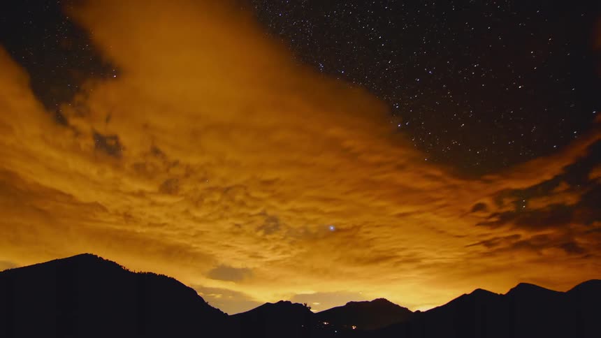 Time lapse of sunset over mountains under starry night