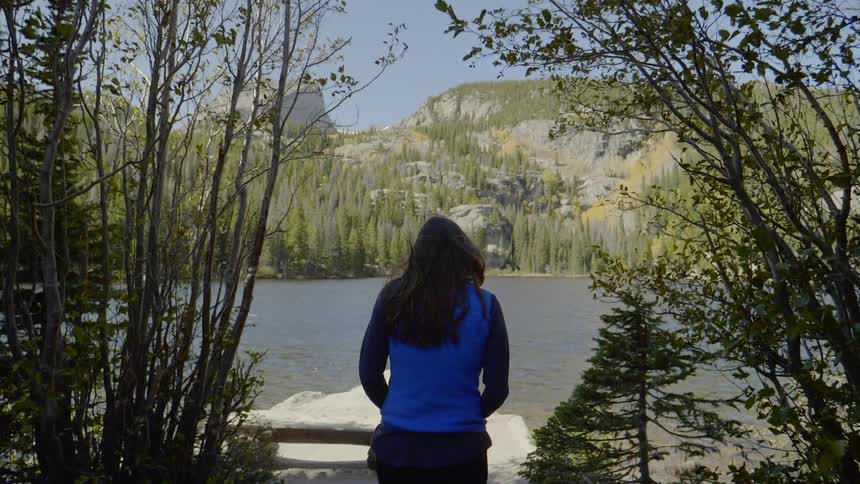 Woman with blue sweater walking towards the lake