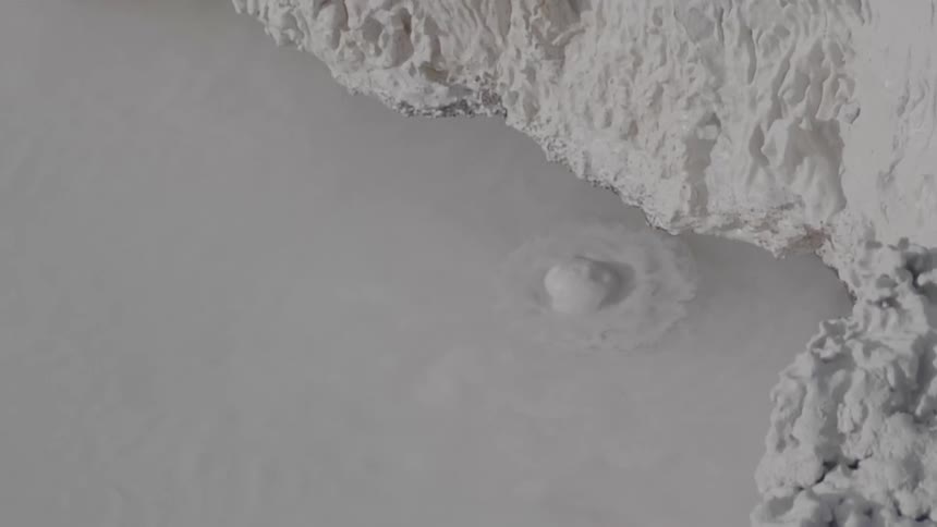 Muddy water bubbles up near white rocky cliffs