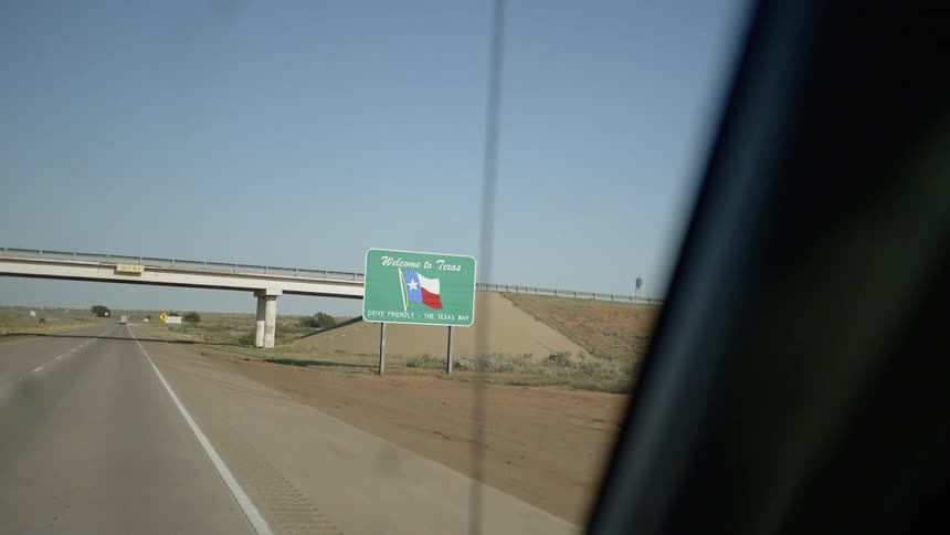 While driving along a desert road a sign by the side of the road welcomes drivers to the state of texas