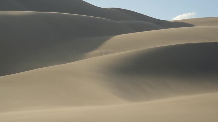 Wind blowing over sand dunes on desert