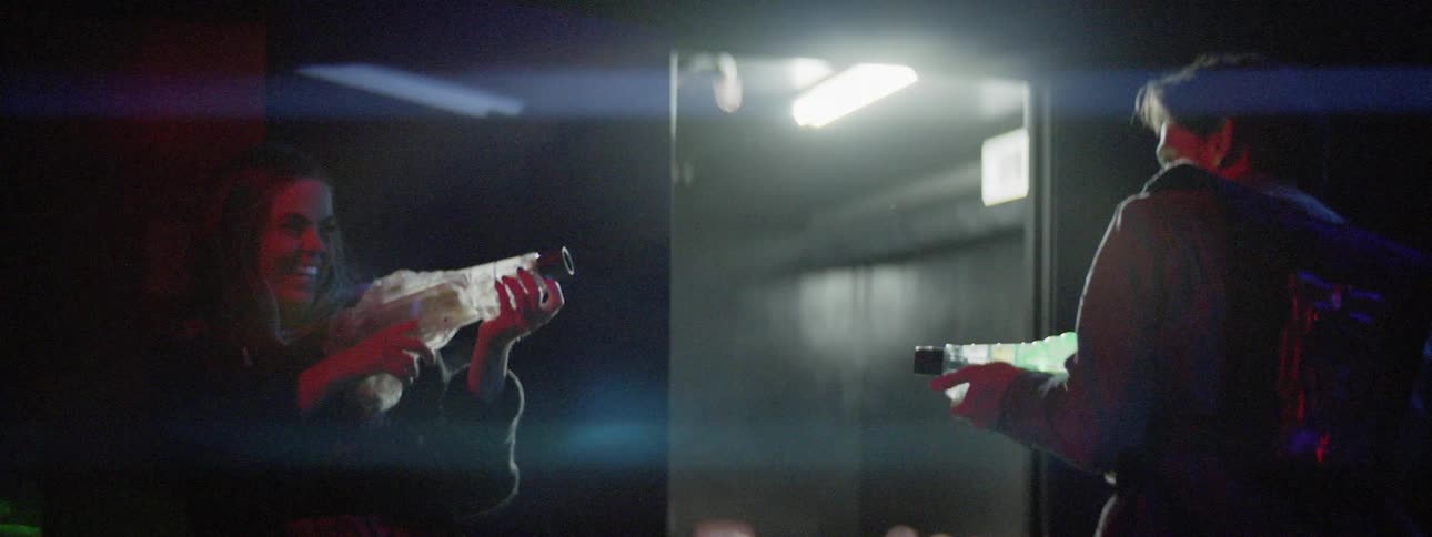 Man and woman play laser tag in a dark room