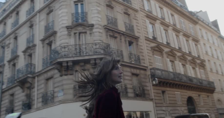A woman runs in front of a large apartment building in a city