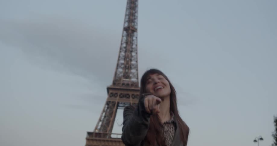 A woman is dancing in front of the eiffel tower