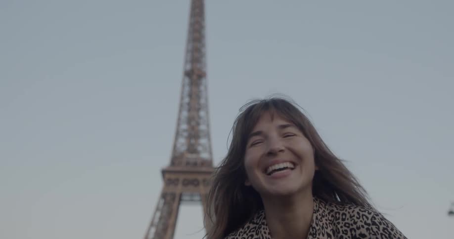 A woman is smiling outdoors by the eiffel tower