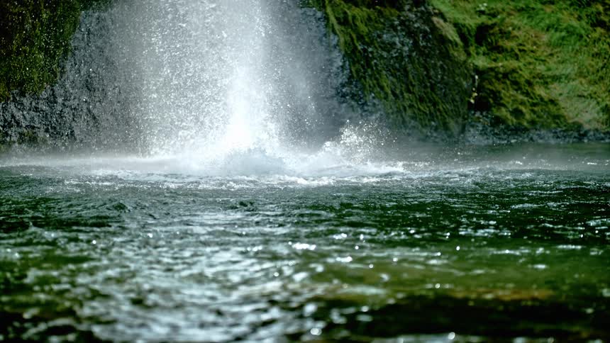A waterfall splashes into a calm pool of water at the foot of a rocky face