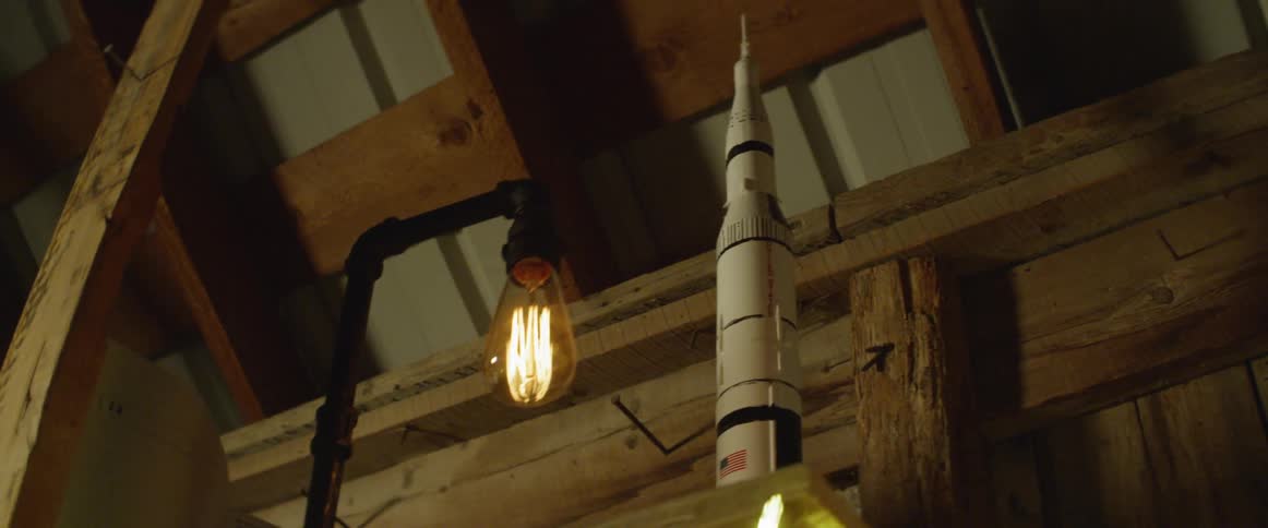 Rocket model and electric bulb in front of rafters and support beams