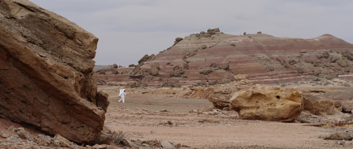 An astronaut leaps across a desert landscape