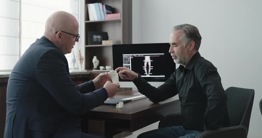 Two men talk about a bone sculpture in an office